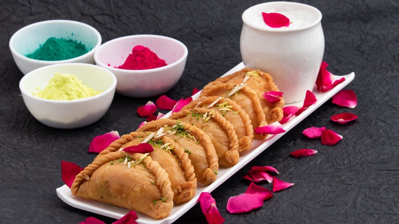 gujiya on white tray flower petals