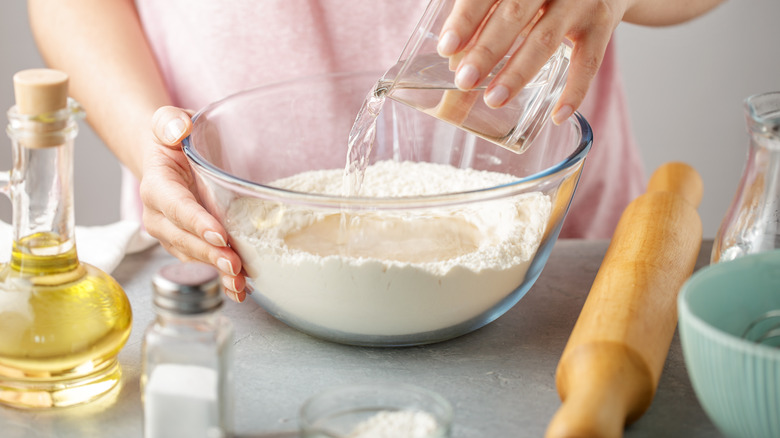 pouring water into bowl of flour