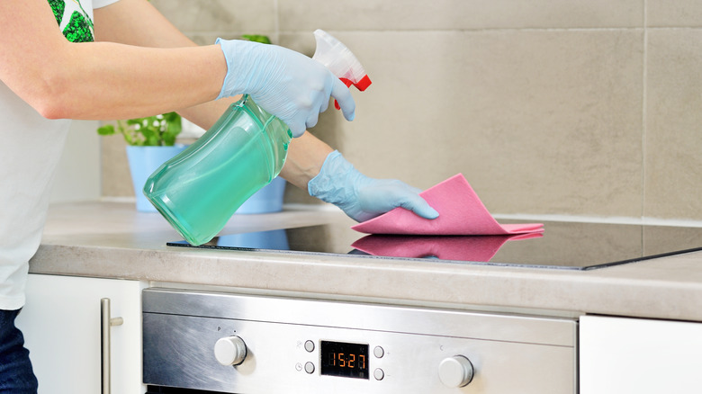 Gloved hands cleaning an electric glass stovetop