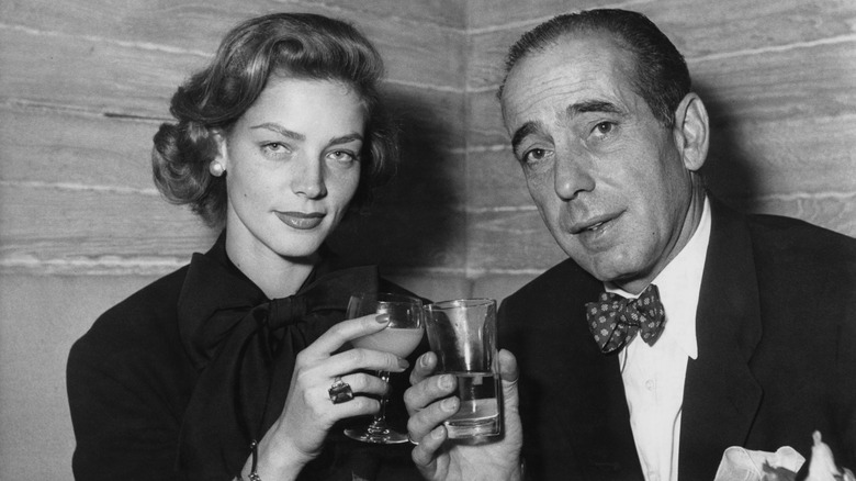 Humphrey Bogart clinking glasses with wife Lauren Bacall