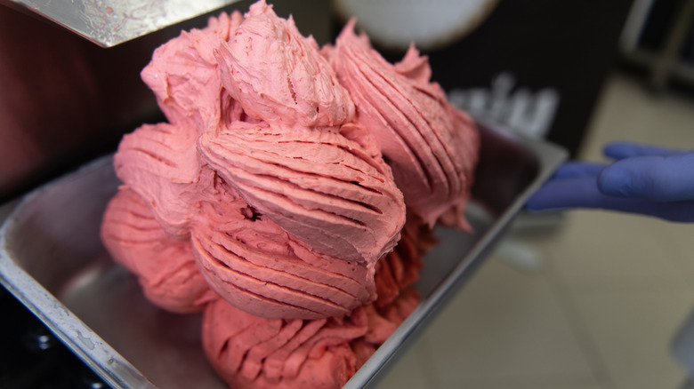 strawberry gelato in metal container with gloved hand