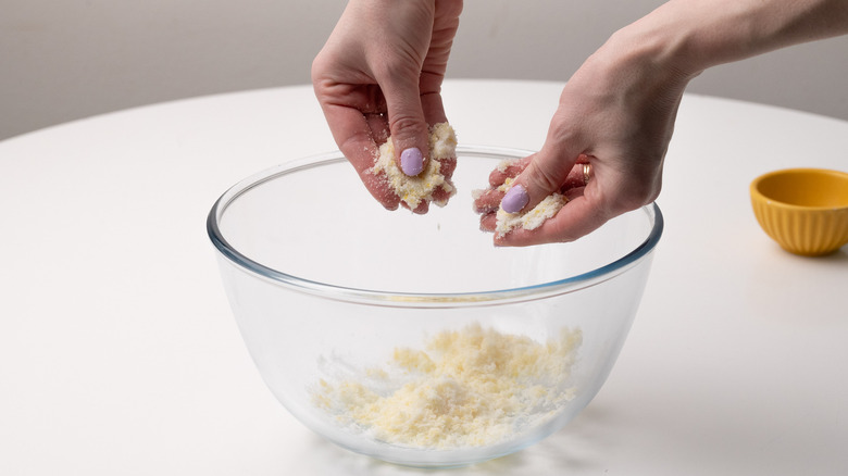 hands massaging lemon zest and sugar over bowl