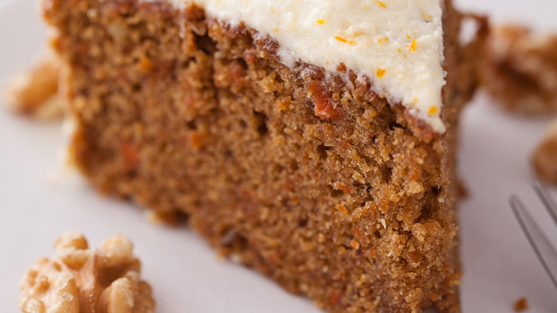Slice of cake on a plate with icing and nuts