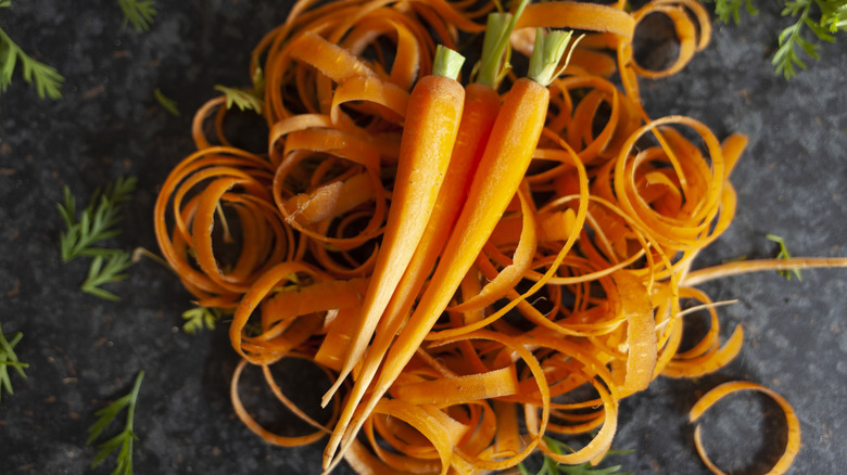 Three carrots on top of a nest of curled carrot peelilngs