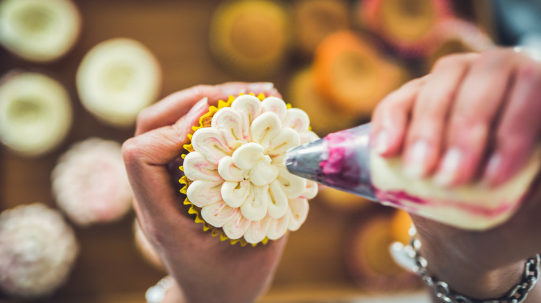 Piping frosting onto cupcake