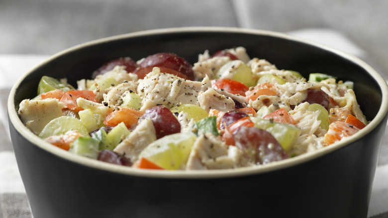 chicken salad with apricots and grapes in a black bowl