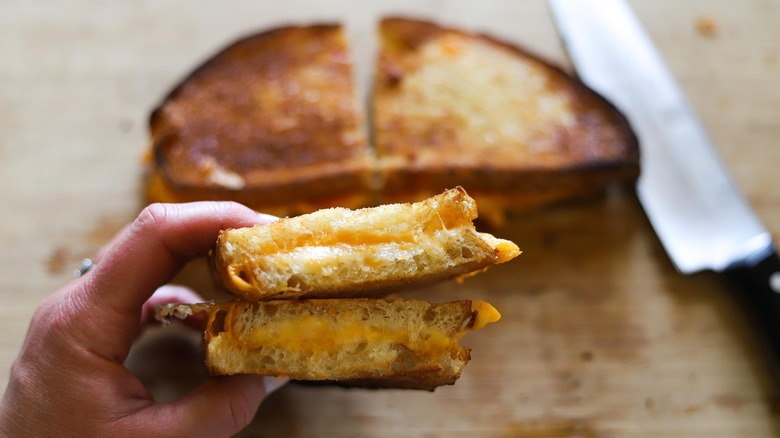 hand holding halved grilled cheese sandwich