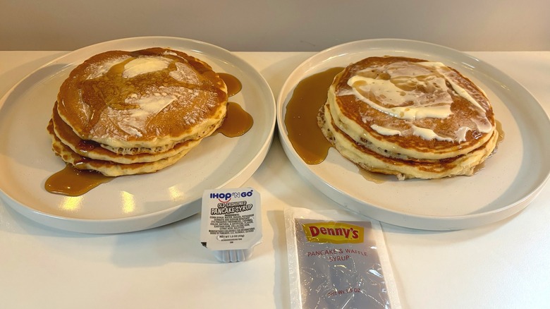 Two white plates of IHOP and Denny's pancake stacks next to syrup packets