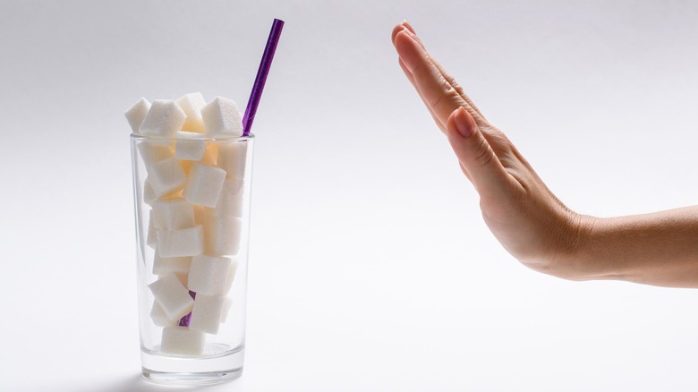 hand and glass of sugar cubes