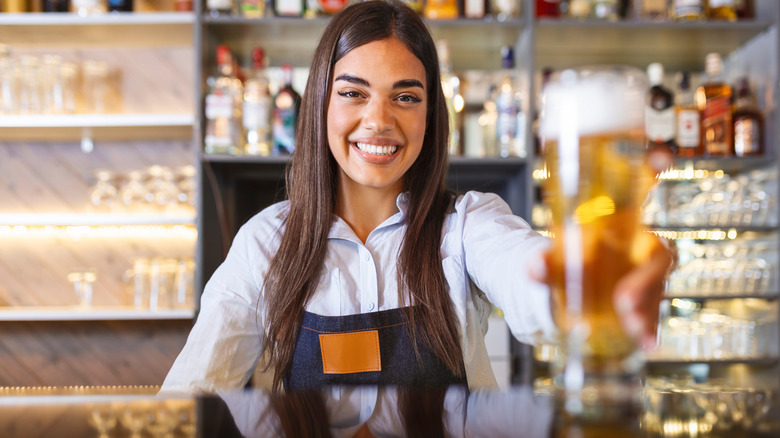 smiling bartender serving a beer