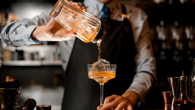 bartender pouring cocktail into glass