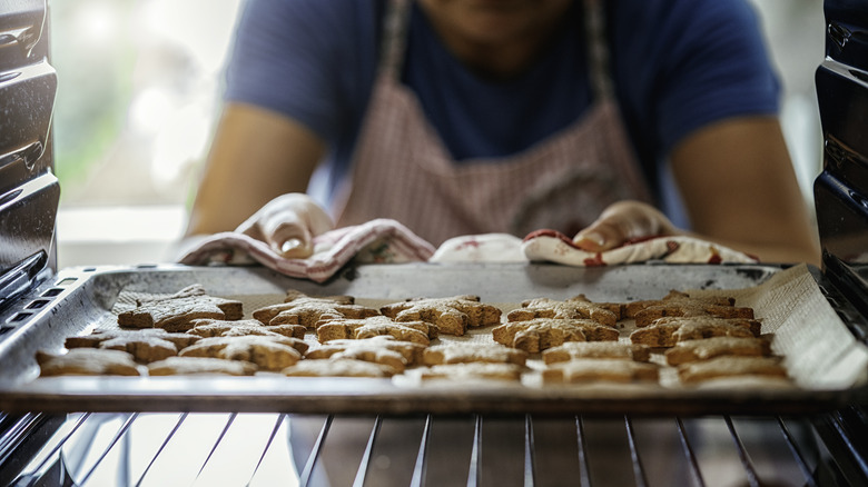 Person putting cookies in oven