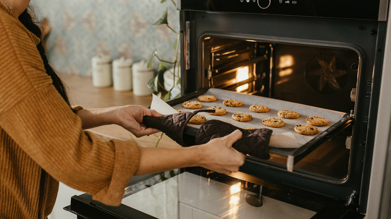 Person baking cookies in oven