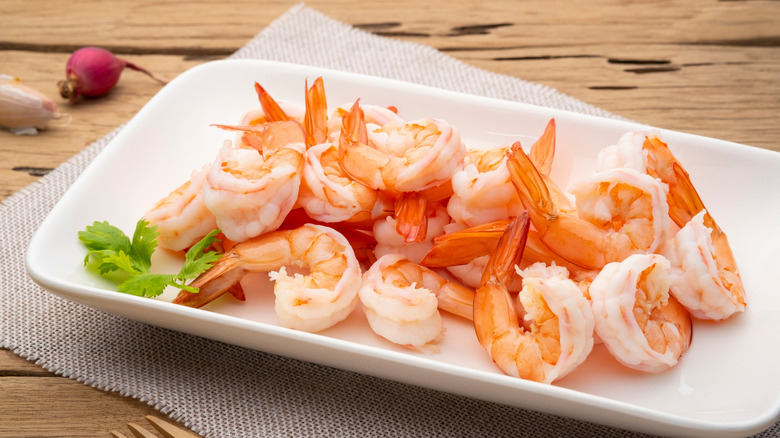 Pink tail-on shrimp arranged on a white platter