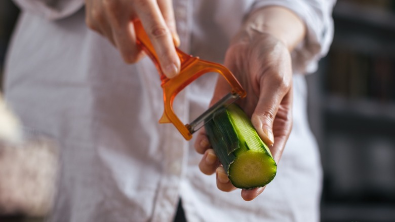 hands peeling a cucumber