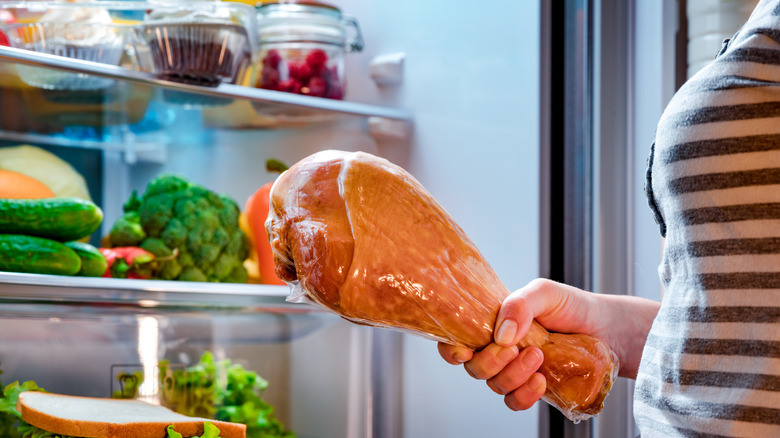 woman with turkey leg from fridge