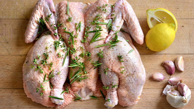 Raw spatchcocked chicken and ingredients on cutting board