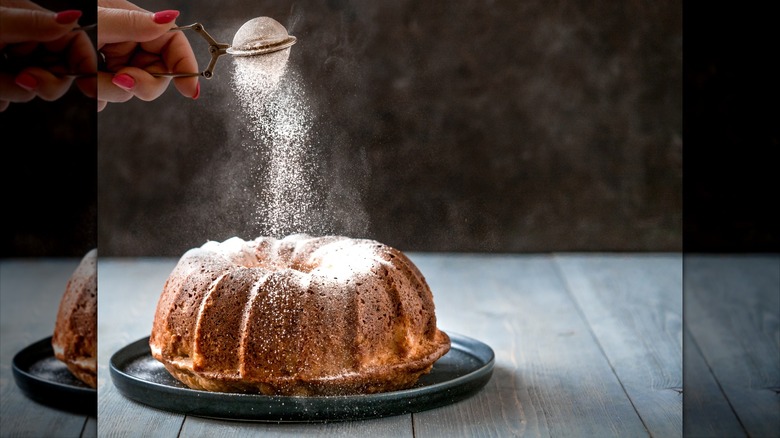 baker decorating cake with powdered sugar