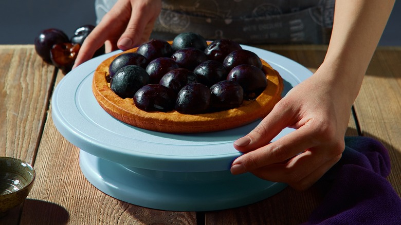 Hands spinning a pie on a rotating cake stand 