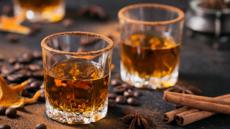 Two shots of bourbon with coffee beans and spices