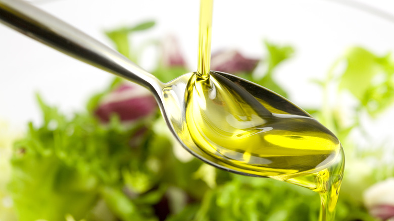Pouring olive oil over salad 