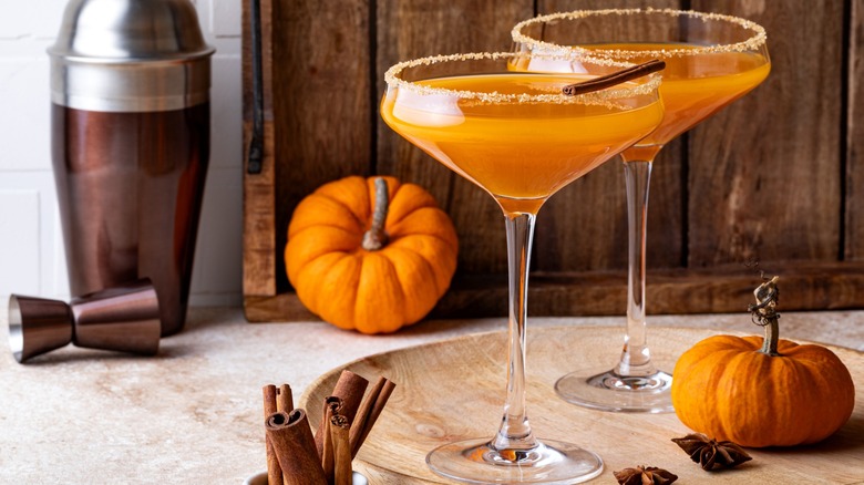 Two pumpkin cocktails with mini pumpkins and cinnamon sticks