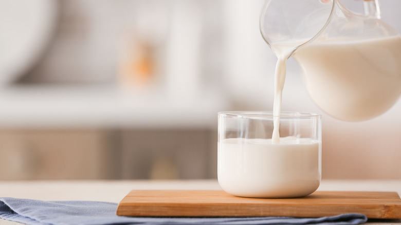 glass pitcher pouring whole milk