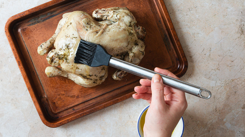 Brushing chicken on baking dish with butter