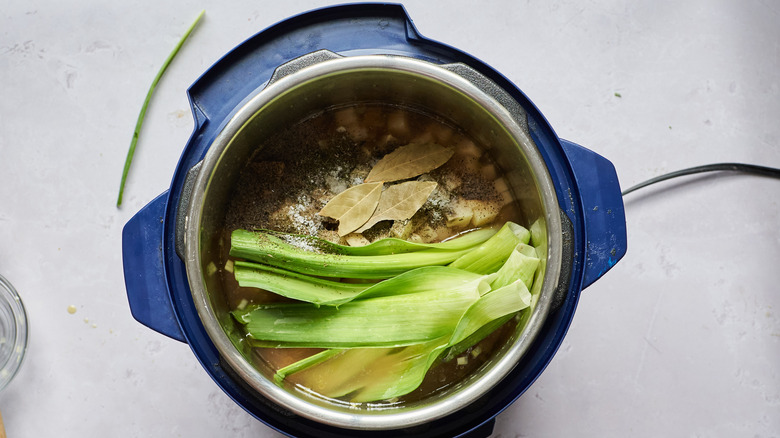 adding broth and potatoes to pot