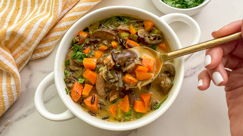 hand with spoon in soup