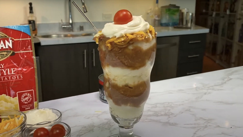 A hot beef sundae in a glass on a kitchen countertop