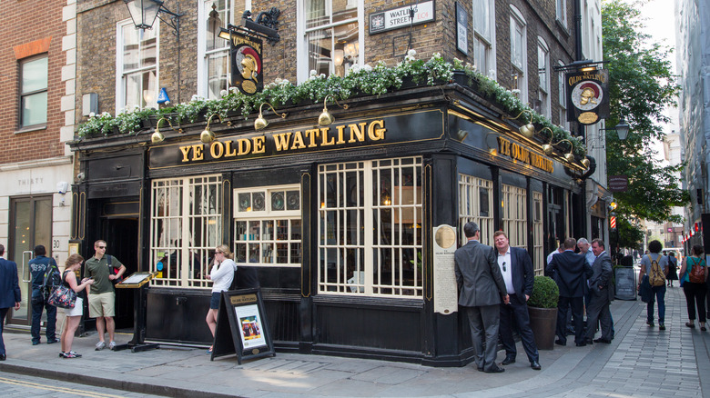 People standing outside of Ye Olde Watling pub in London, England