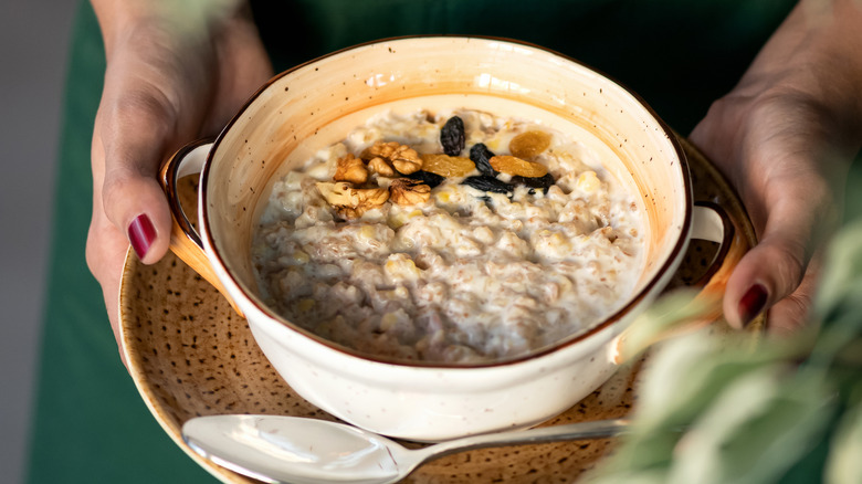 holding a bowl of oats with dried fruit