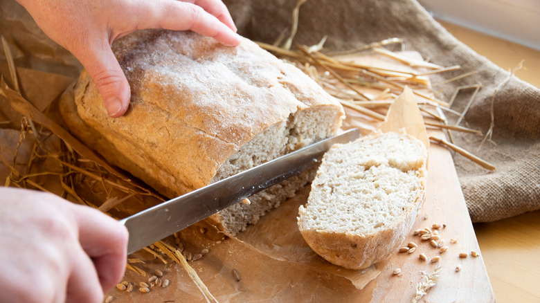 man cutting loaf of bread