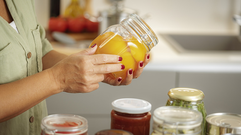 Hands holding a jar of canned peaches
