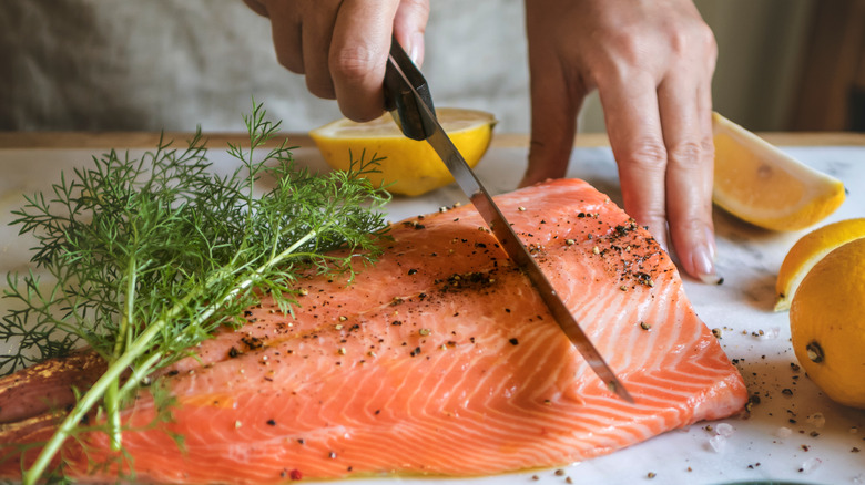 slicing salmon fillet on cutting board 