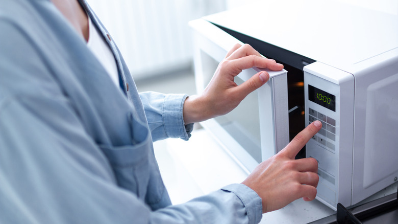 person pushing microwave button