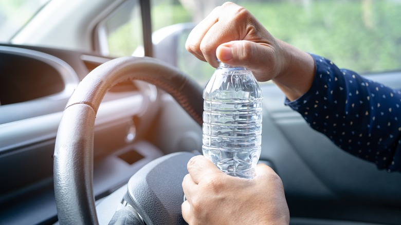 Hands holding a plastic water bottle in car