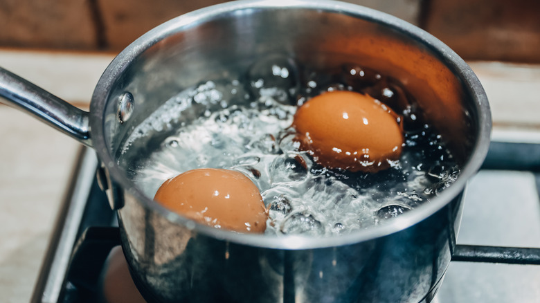 Brown eggs boiling in a silver pot