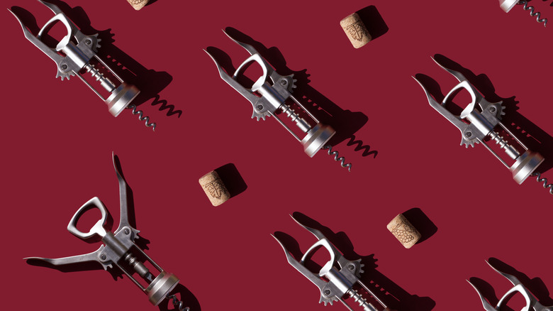corks and cork screws against wine colored backdrop