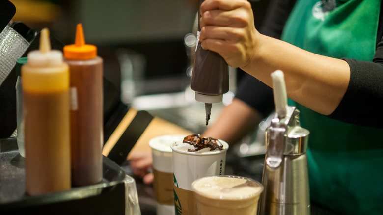 Starbucks barista squeezing syrup into drink