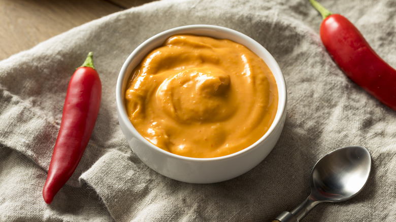 Dish of homemade spicy mayo between two chili peppers