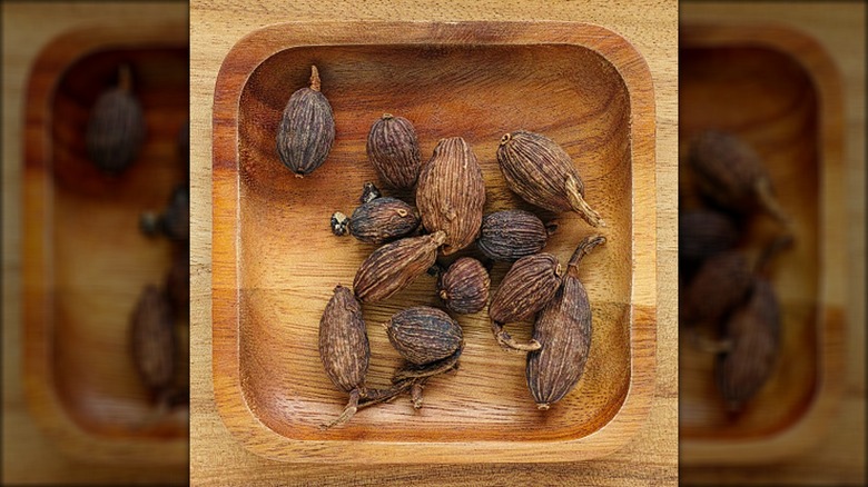 Top-down view of black cardamom pods in a wooden tray