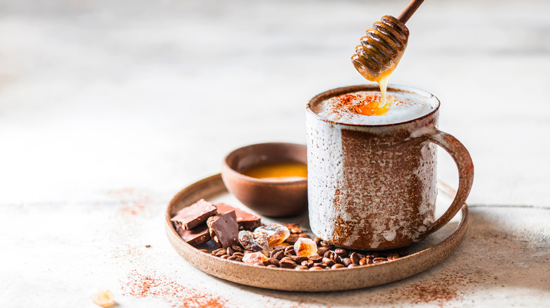 Pouring honey into chocolate coffee