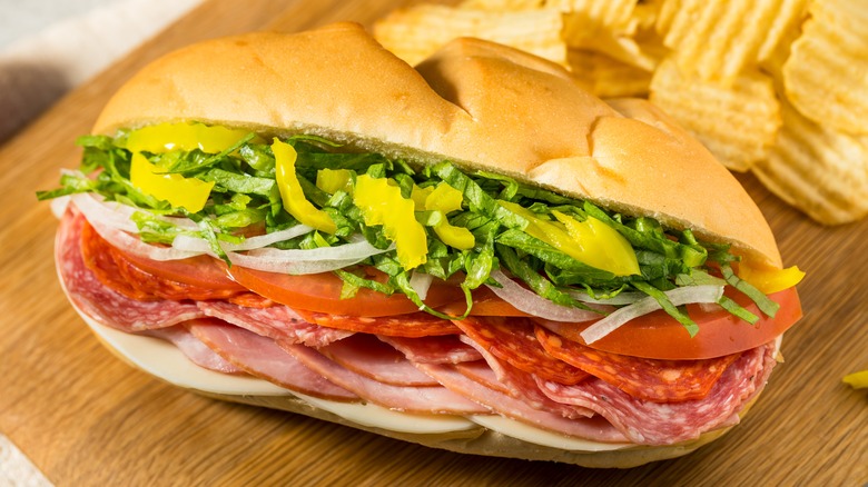 Italian sub sandwich on wood table with potato chips