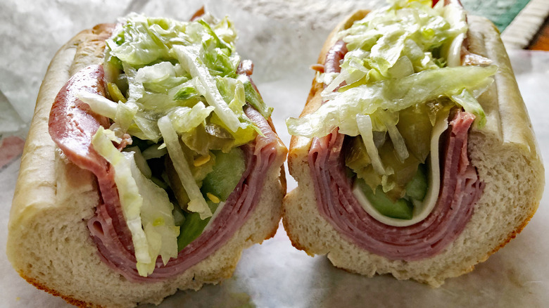 Sub sandwich with meat, cheese, and lettuce cut in half