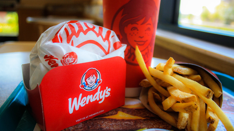 Wendy's order with burger, fires, and drink on tray inside restaurant