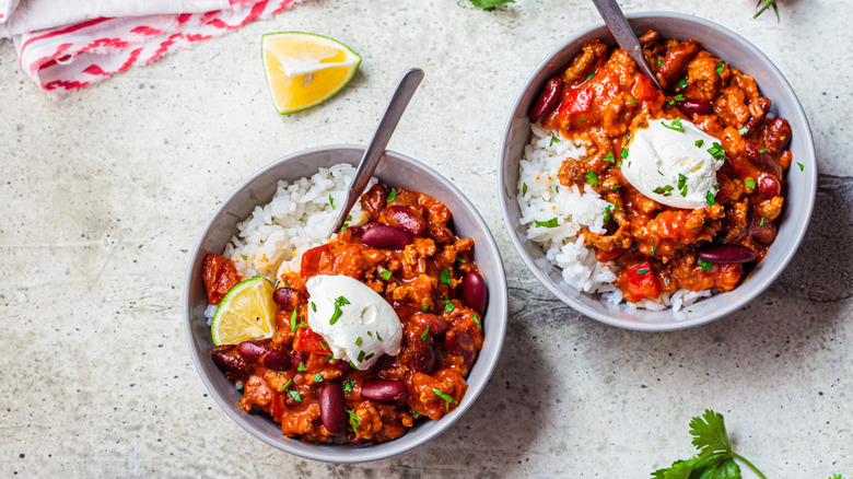 two bowls of chili with rice and sour cream