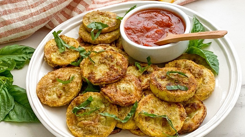 fried squash on round plate with basil and sauce