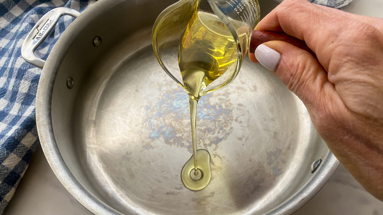 hand adding oil to pan